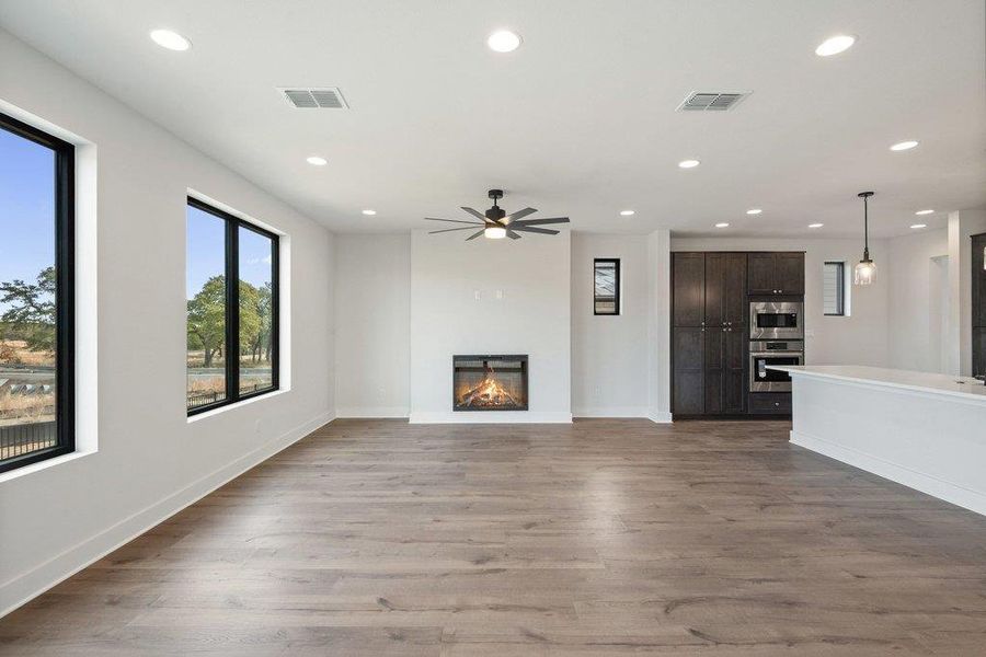 Unfurnished living room with recessed lighting, light wood finished floors, a glass covered fireplace, and ceiling fan