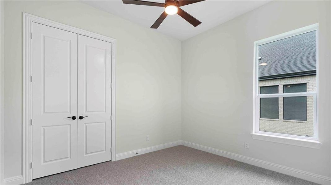 Room featuring neutral wall tones, gray carpet, a ceiling fan with integrated lighting, and a double-pane window