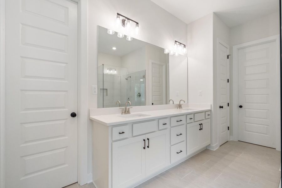 Dual vanity with white cabinetry, light-toned countertop, and brushed nickel fixtures