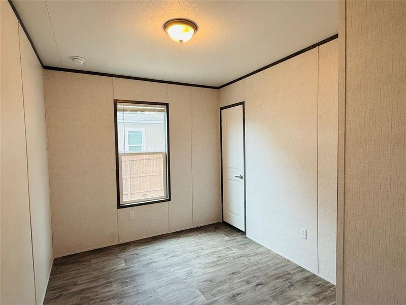 Empty room with wood finished floors, crown molding, and a decorative wall