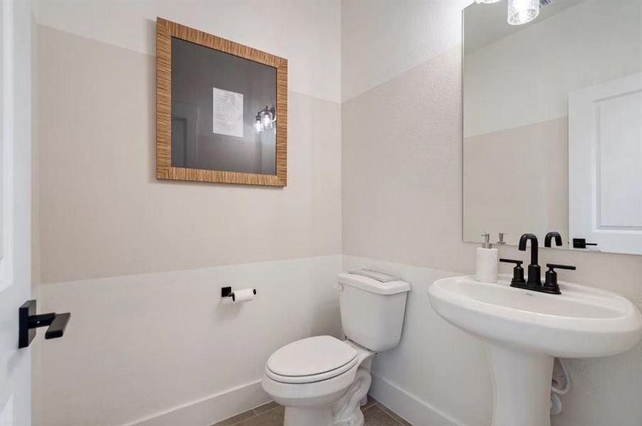 Half bath featuring toilet, baseboards, and a sink
