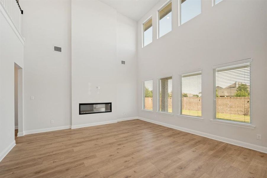 Spacious living area featuring a two-story ceiling, a modern linear fireplace, and wood-finish flooring