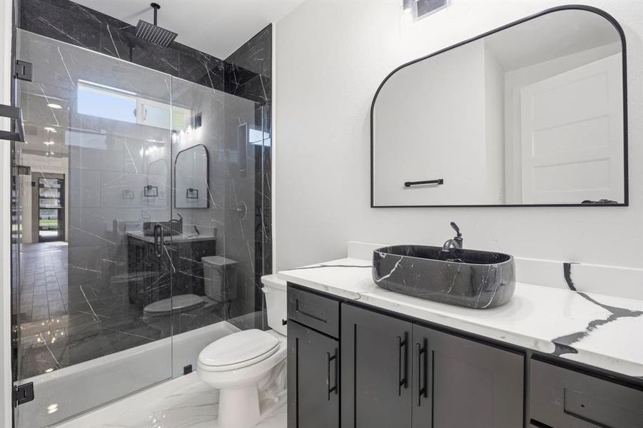 Modern bathroom featuring a glass-enclosed shower with black-tiled walls and a rainfall showerhead Modern bathroom featuring a glass-enclosed shower with black-tiled walls and a rainfall showerhead