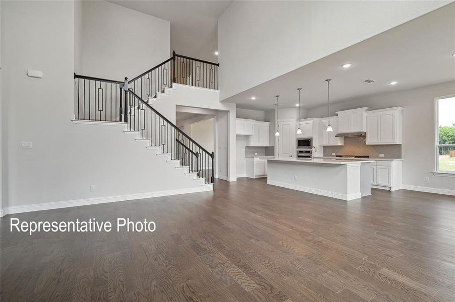 Unfurnished living room with a high ceiling and dark wood-type flooring