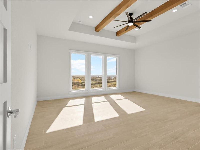 Primary bedroom with exposed wood beams and tray ceiling