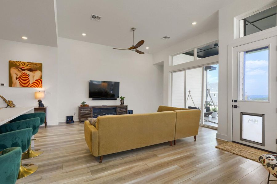 Natural light floods this inviting living area, showcasing its soaring ceilings and sleek LVP flooring.