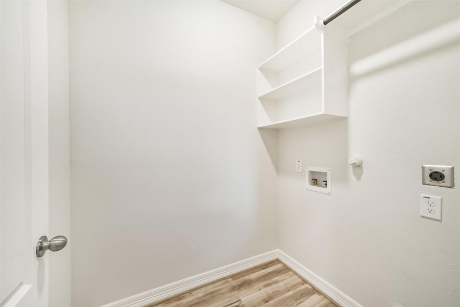 The laundry room offers washer and dryer connections, vinyl plank flooring, and a built in shelving unit with a hanging rack. The laundry room offers washer and dryer connections, vinyl plank flooring, and a built in shelving unit with a hanging rack.