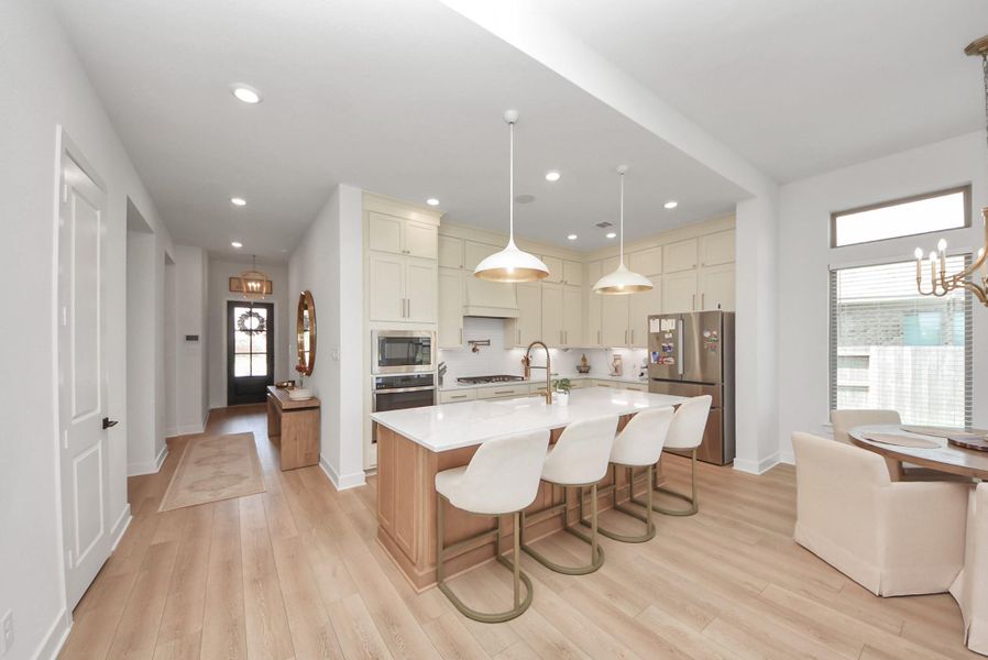 Bright and modern kitchen featuring a large island with seating, sleek appliances, and ample cabinetry, seamlessly connected to a cozy dining area.