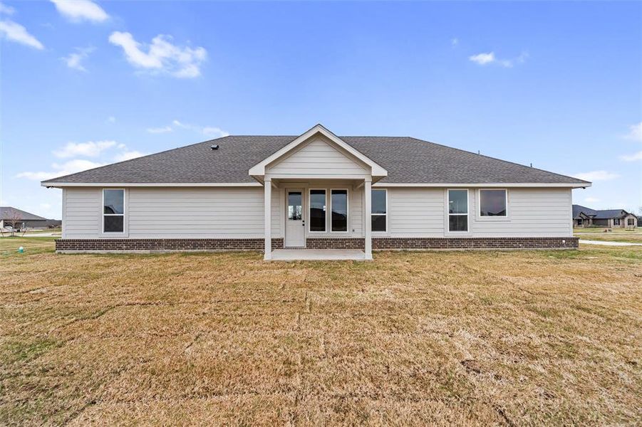 Rear view of house featuring a lawn, roof with shingles, brick siding, and a patio Rear view of house featuring a lawn, roof with shingles, brick siding, and a patio