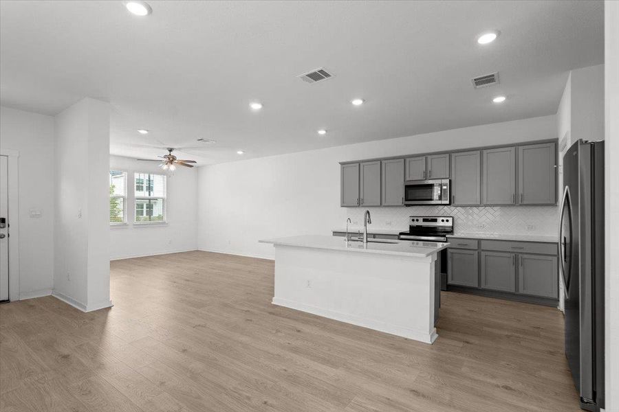 An open floorplan seamlessly connects the kitchen with stainless steel appliances to the bright living area.