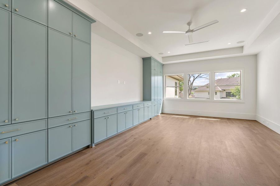 A spacious upstairs flex area features custom built-in cabinetry along one wall, offering both storage and display. Large windows bring in natural light, creating a versatile space for recreation or relaxation.