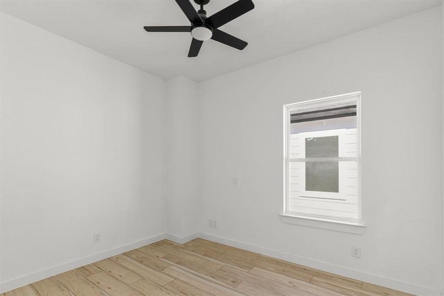 Secondary bedroom featuring light wood-type flooring, baseboards, and a ceiling fan