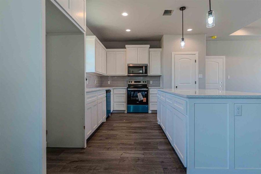 Kitchen featuring recessed lighting, tasteful backsplash, stainless steel appliances, white cabinets, and dark wood-type flooring Kitchen featuring recessed lighting, tasteful backsplash, stainless steel appliances, white cabinets, and dark wood-type flooring