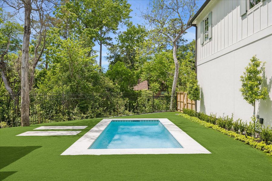 Gorgeous poolside setting bordered by iron fencing that frames the lush, wooded backdrop of the ravine. Turf and designated relaxation areas overlook the serene natural view beyond the yard. We love this privacy!!