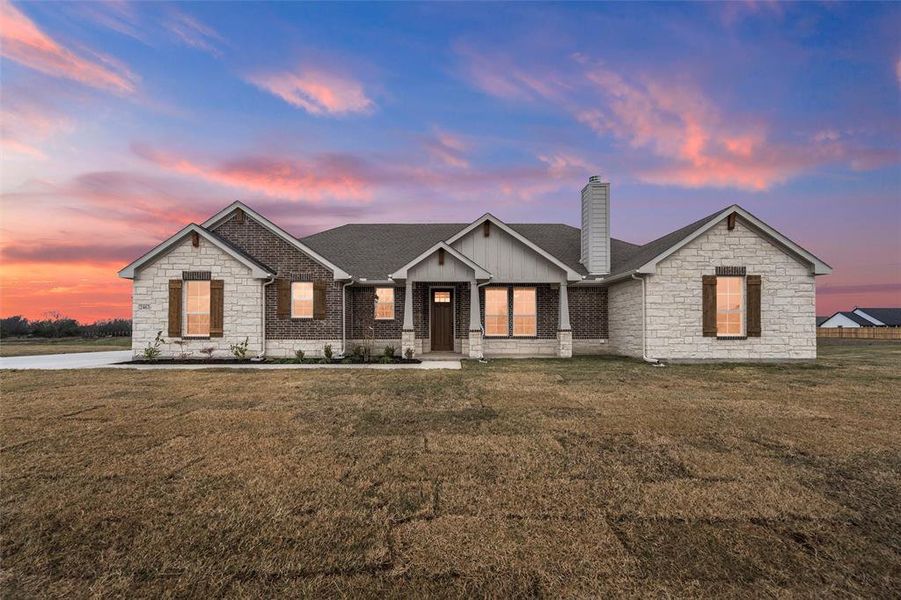 View of front of home with a front lawn, a porch, stone siding, and a chimney View of front of home with a front lawn, a porch, stone siding, and a chimney