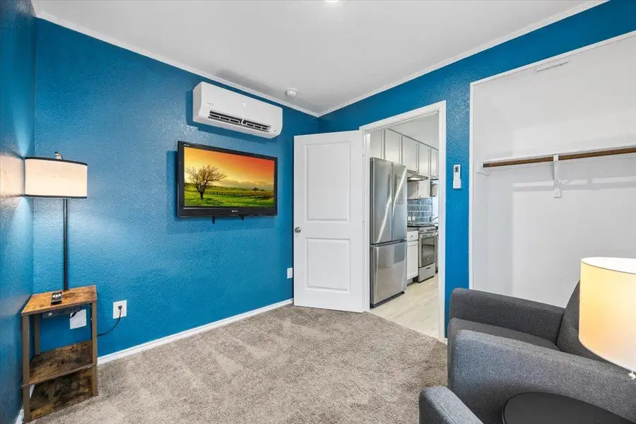 Sitting room featuring light colored carpet, a textured wall, and a wall mounted mini split Sitting room featuring light colored carpet, a textured wall, and a wall mounted mini split