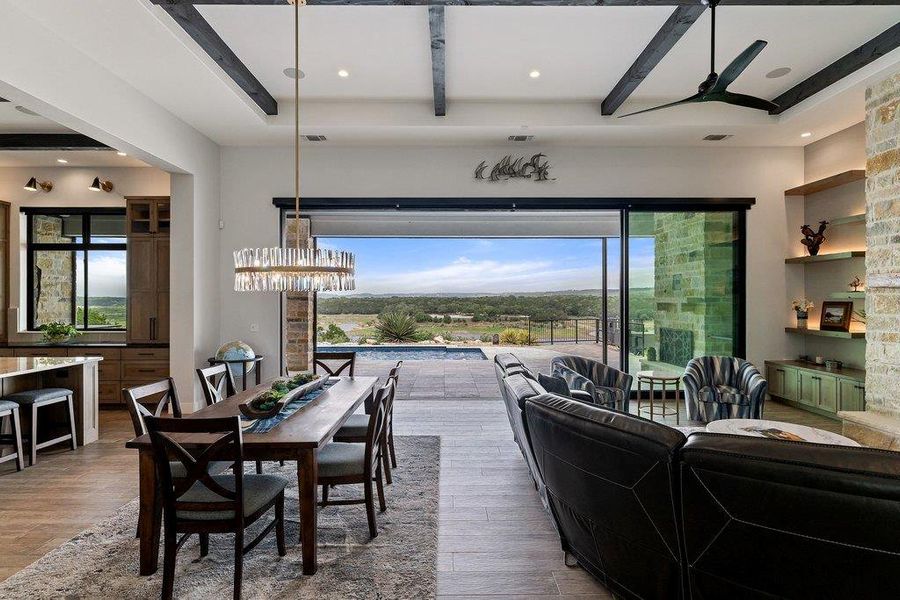 The dining area, anchored by a tiered crystal chandelier, flows seamlessly onto the covered patio through expansive sliding glass