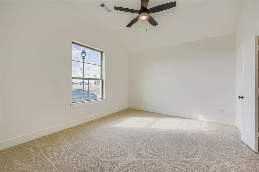 Empty room featuring lofted ceiling, light carpet, and ceiling fan Empty room featuring lofted ceiling, light carpet, and ceiling fan
