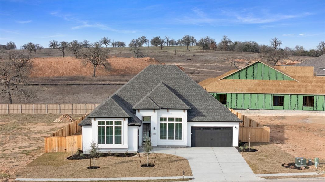 View of front of house with roof with shingles, driveway, an attached garage, and stucco siding
