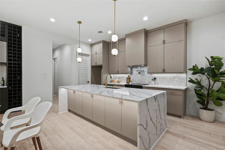 Kitchen featuring sink, gray cabinets, an island with sink, light stone countertops, and light hardwood / wood-style floors