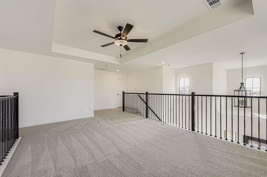 Carpeted empty room with a tray ceiling and ceiling fan