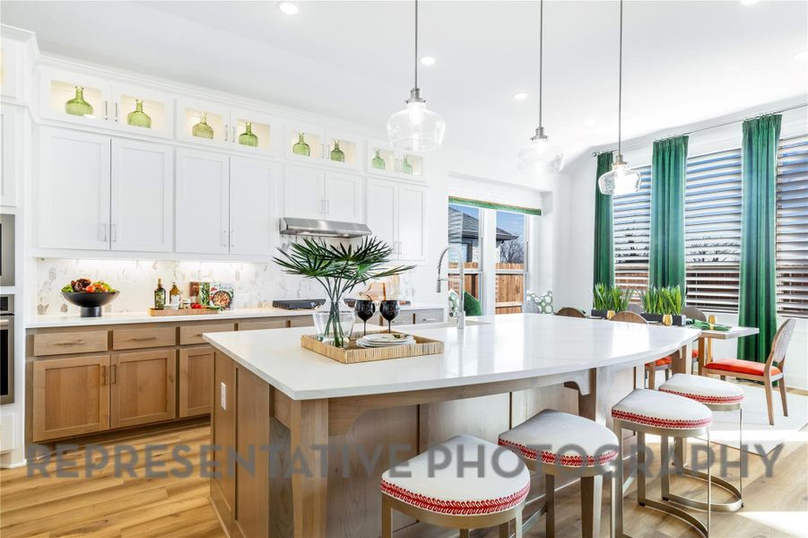 Kitchen featuring light wood-style floors, light countertops, tasteful backsplash, and a breakfast bar area Kitchen featuring light wood-style floors, light countertops, tasteful backsplash, and a breakfast bar area