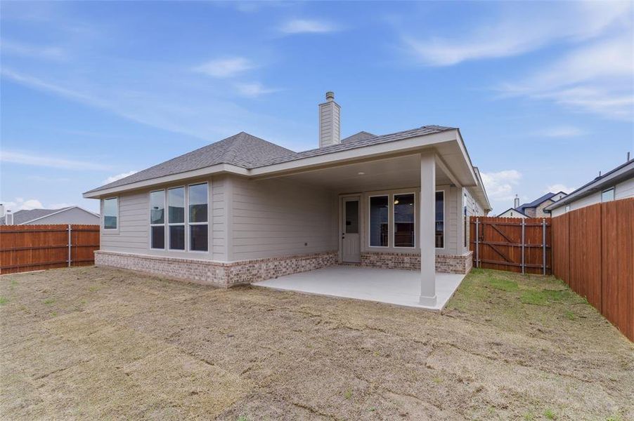 Back of property with brick siding, a gate, a fenced backyard, a patio area, and a chimney