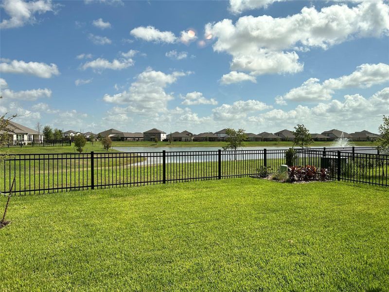 Private Backyard Retreat — Spacious backyard with wrought-iron fencing for added privacy and peaceful views of the scenic waterfall and pond.