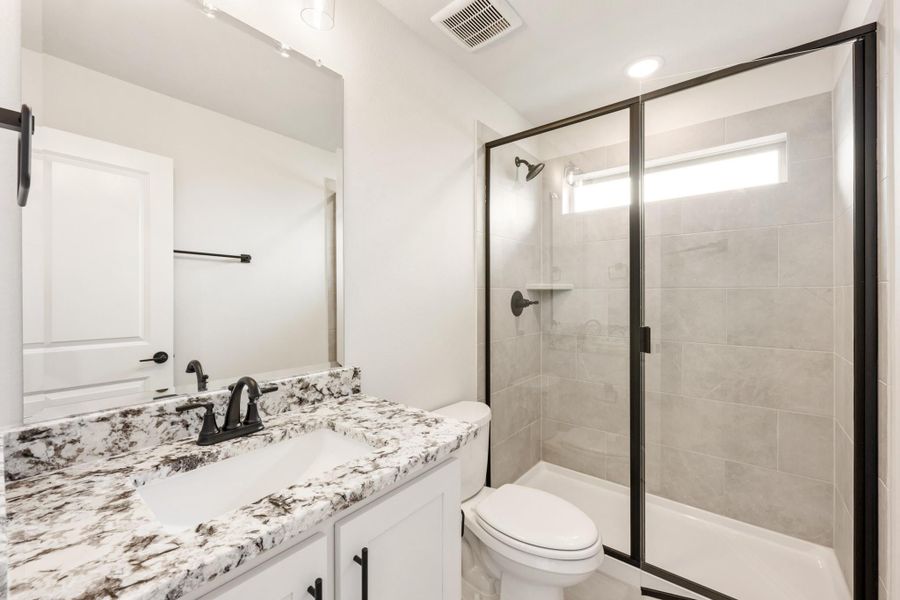 Bathroom with granite countertop vanity, glass-enclosed tile shower, and black fixtures Bathroom with granite countertop vanity, glass-enclosed tile shower, and black fixtures