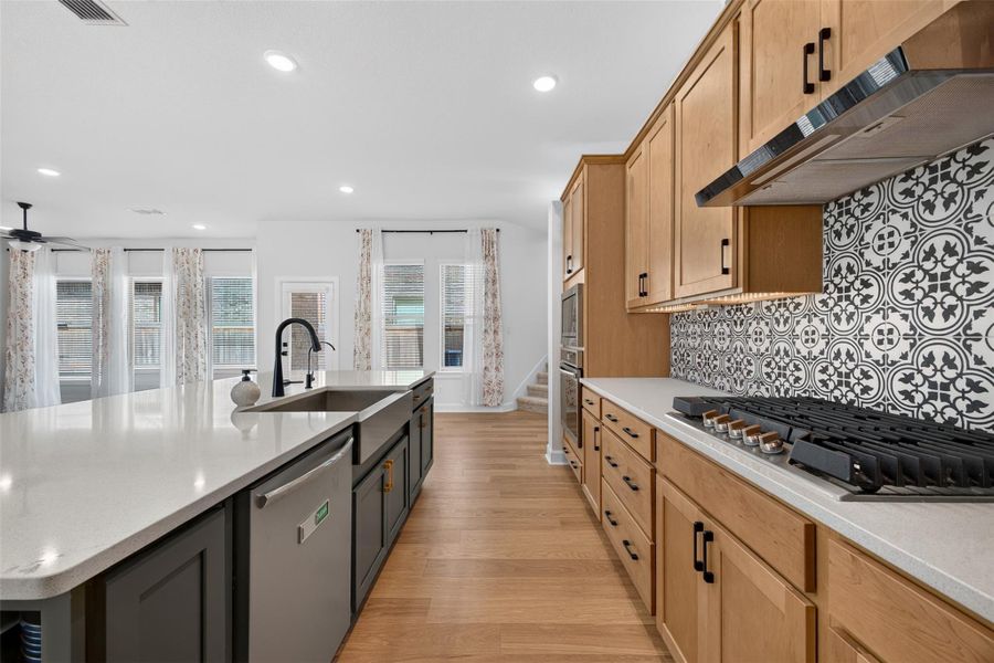 The open-concept kitchen blends contemporary style with premium functionality, featuring sleek stainless steel appliances, a built-in convection oven and microwave, a gas cooktop, a built-in water filtration system, generous counter space, and abundant cabinetry. Filled with natural light and seamlessly connected to the dining and living areas, it's a space designed to bring people together, including side patio area access, making everyday living and entertaining feel effortless.