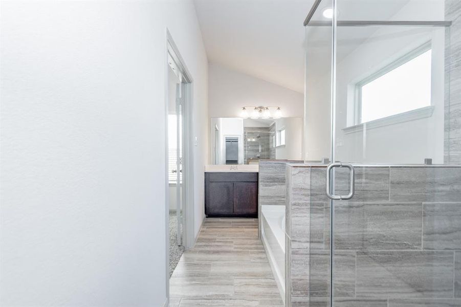 This view highlights the seamless integration of the glass-enclosed shower and soaking tub. The open design and neutral color palette create a serene and inviting space. Dual vanities add convenience and functionality, making this bathroom ideal for busy mornings or relaxing evenings.