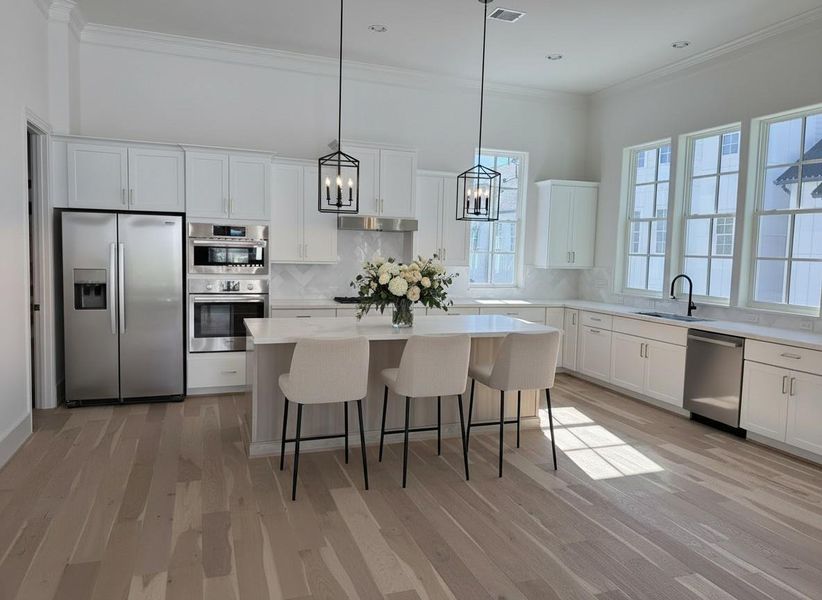 Stunning huge kitchen iwth 4 windows and flooded with natural light and plenty of cabient space. Upgraded pendant lighting and white marble herringbone backsplash and SS Bosch appliances