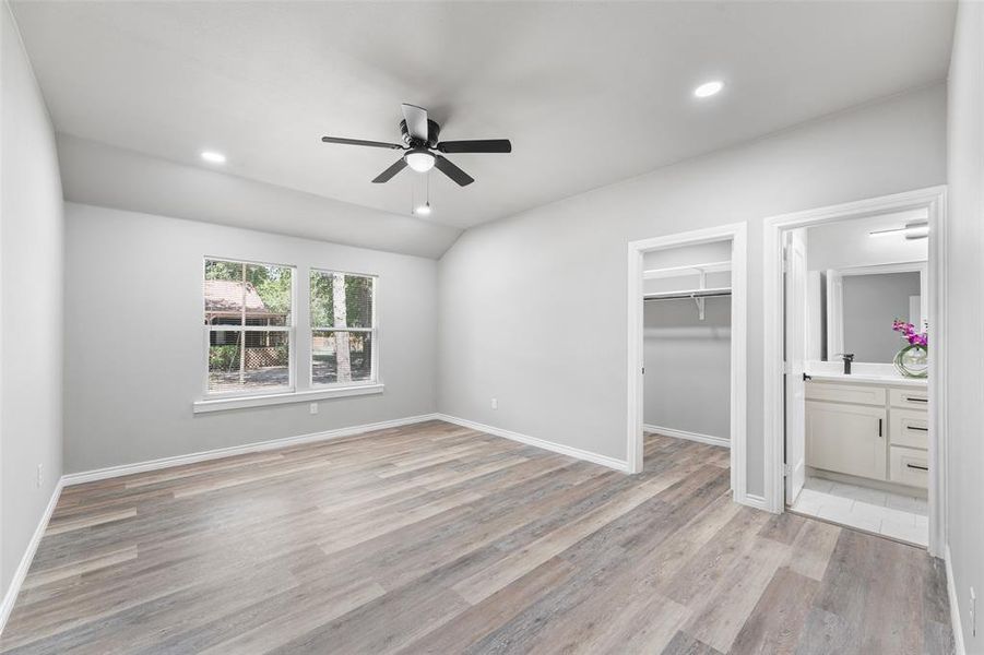 Spacious room featuring wood-finish flooring, vaulted ceilings, and recessed lighting Spacious room featuring wood-finish flooring, vaulted ceilings, and recessed lighting