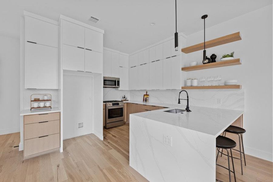 Kitchen with modern cabinets, white cabinetry, open shelves, light stone counters, and a peninsula