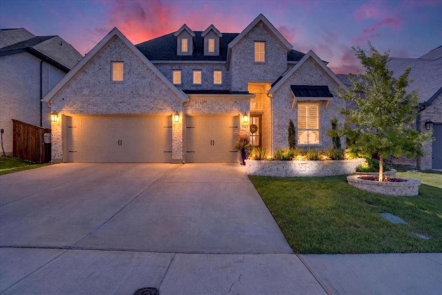 Stone facade residence featuring a double-bay garage, dormer windows, and a concrete driveway Stone facade residence featuring a double-bay garage, dormer windows, and a concrete driveway