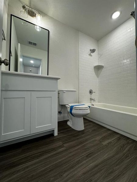 Full bathroom featuring vanity, hardwood / wood-style flooring, toilet, and tiled shower / bath