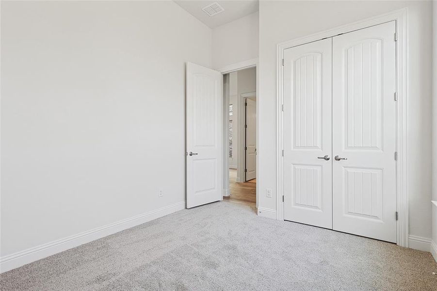 Unfurnished bedroom with light colored carpet and a closet