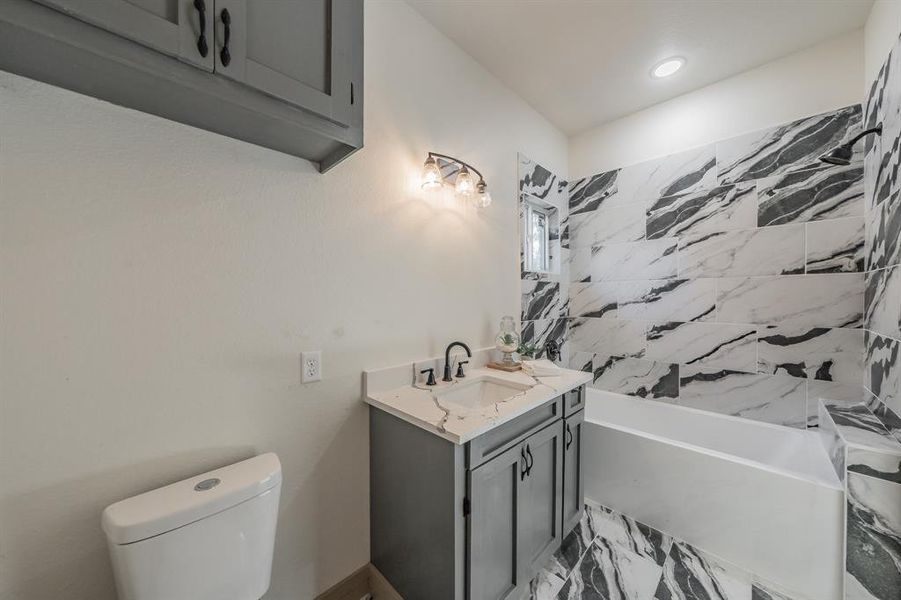 Bathroom featuring vanity, bathing tub / shower combination, recessed lighting, and light marble finish flooring