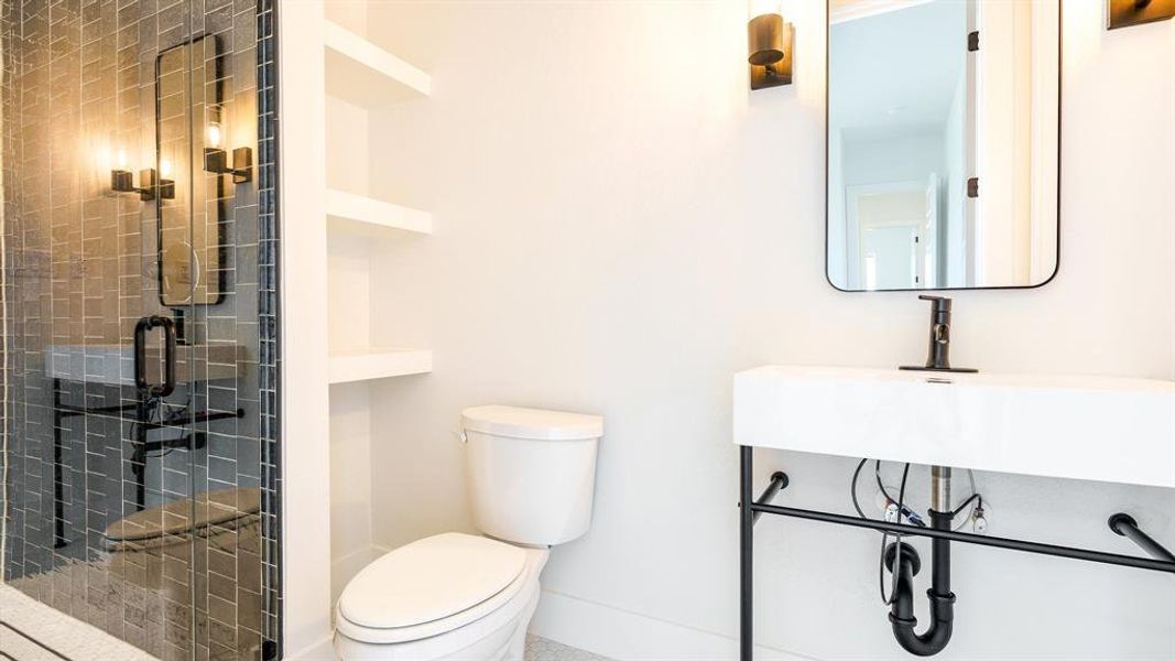 Bathroom featuring sink, toilet, and a shower with shower door