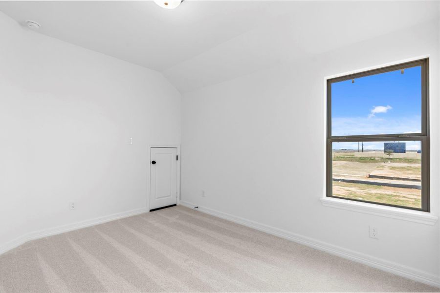 Bright and cozy second bedroom with plush carpet and sun-filled windows.