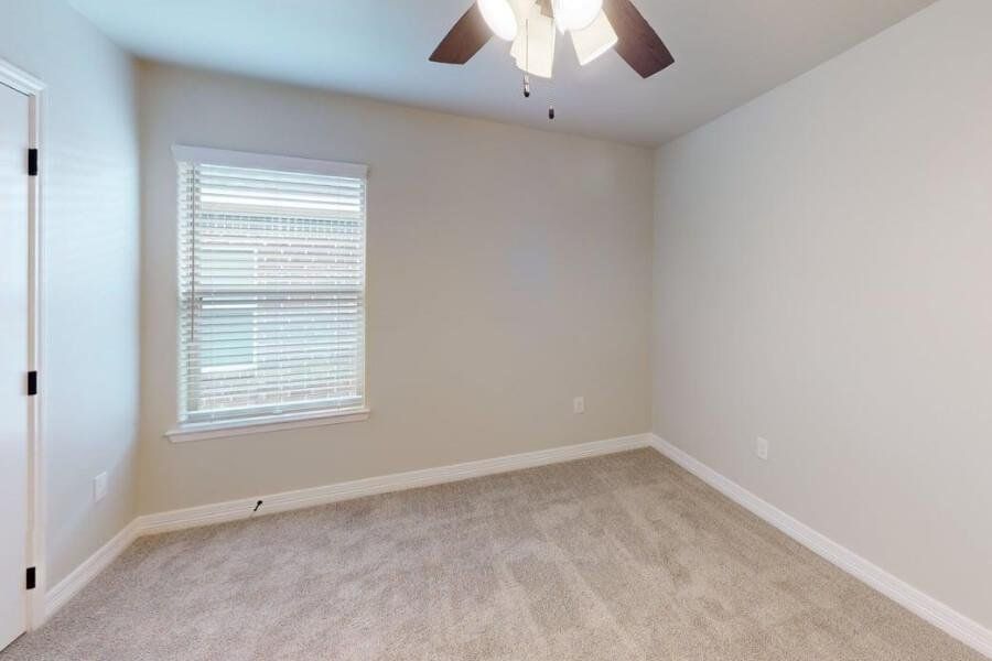Empty room featuring light carpet and a ceiling fan