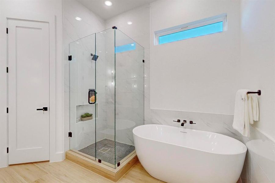 Bathroom with hardwood / wood-style floors and shower with separate bathtub