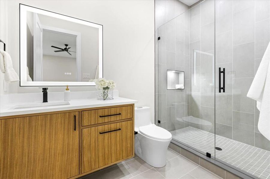 Bathroom featuring vanity, tile patterned floors, ceiling fan, toilet, and a shower with door