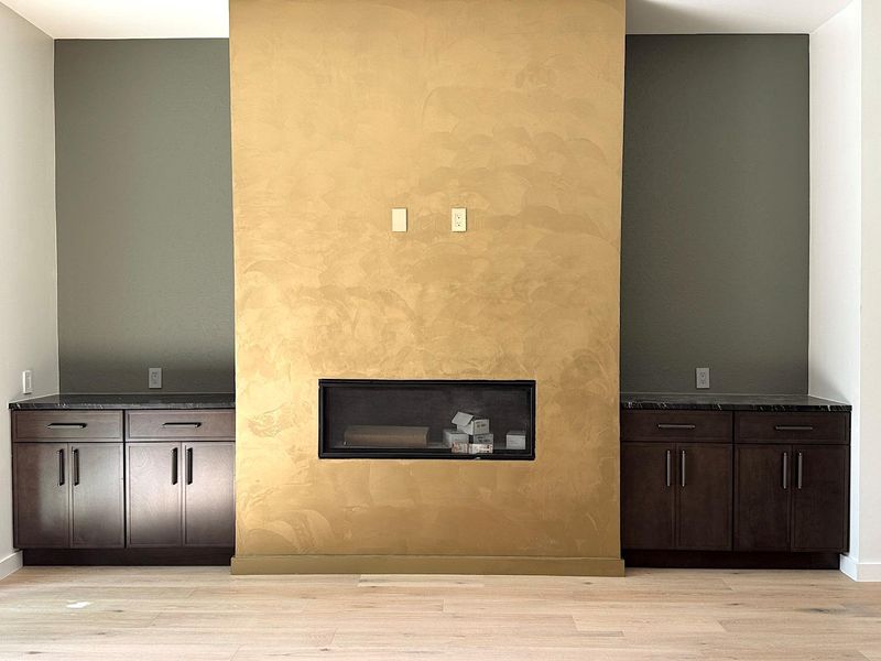 Unfurnished living room featuring baseboards, light wood-style floors, and a glass covered fireplace