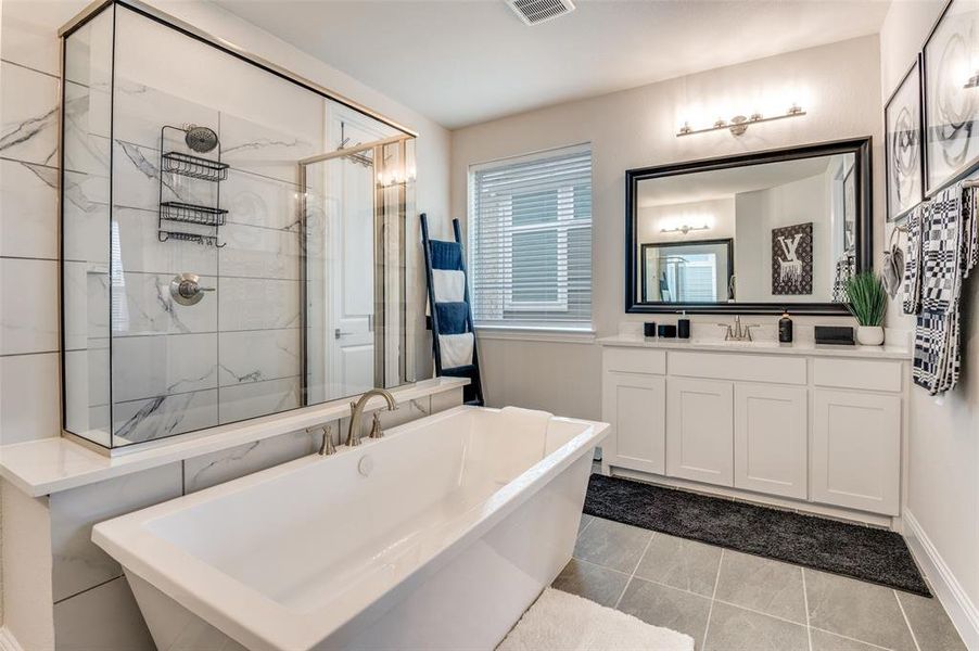 Full bath with a soaking tub, vanity, light tile patterned floors, and a marble finish shower