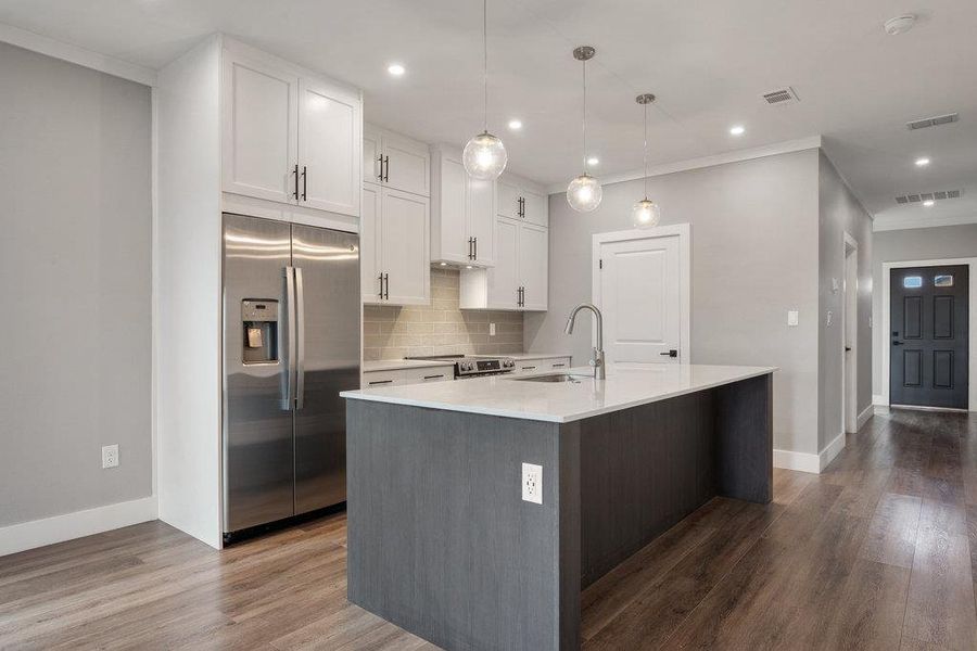 Two tone kitchen featuring stainless steel appliances, tasteful backsplash, dark wood-style flooring, ornamental molding, and two tone color scheme