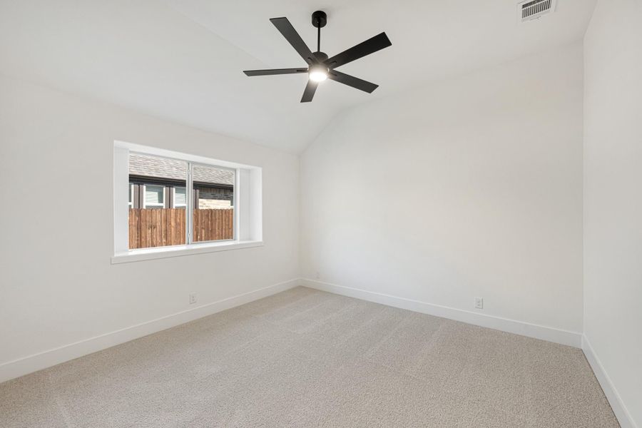 Empty bedroom with vaulted ceiling, black ceiling fan, carpet flooring, and single window