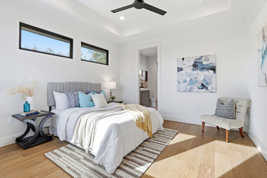 Bedroom with a raised ceiling, wood finished floors, ensuite bath, and recessed lighting Bedroom with a raised ceiling, wood finished floors, ensuite bath, and recessed lighting