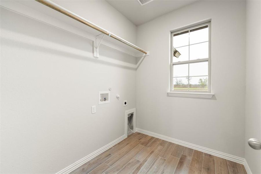 Laundry room featuring hookup for a gas dryer, wood finish floors, electric dryer hookup, and washer hookup Laundry room featuring hookup for a gas dryer, wood finish floors, electric dryer hookup, and washer hookup