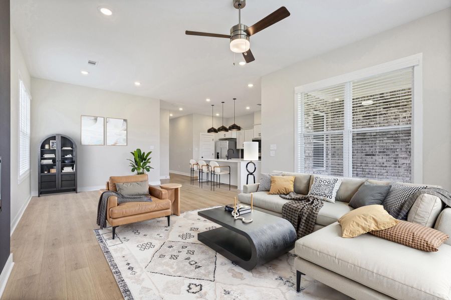 Open-concept living area featuring wood-finish flooring, recessed lighting, and a ceiling fan Open-concept living area featuring wood-finish flooring, recessed lighting, and a ceiling fan